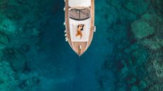 Aerial view of a couple cuddling on a yacht in pretty water.