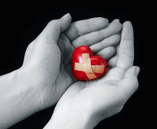 A woman holds an image of a heart in her hands.