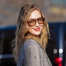 street style shot of woman with highlighted wavy hair and aviator sunglasses on