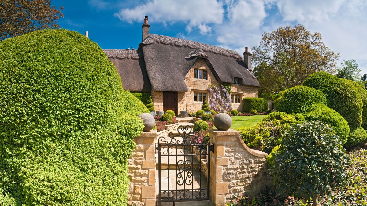 pretty thatched cottage with formal front garden and stone wall