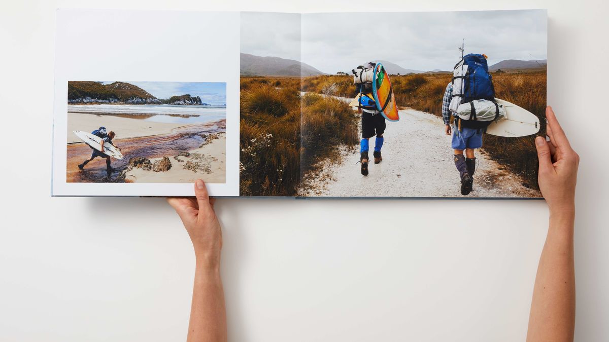 A pair of hands opening a photo book on a table