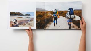 A pair of hands opening a photo book on a table