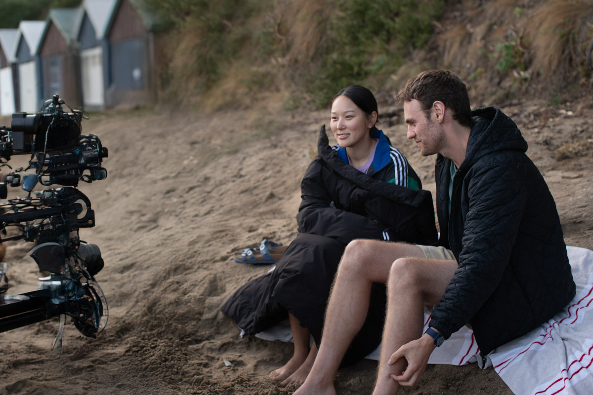 yerin ha and charlie vickers behind the scenes filming a scene on the beach in the survivors