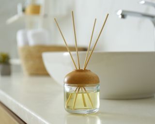 Oil reed diffuser on off-white bathroom counter