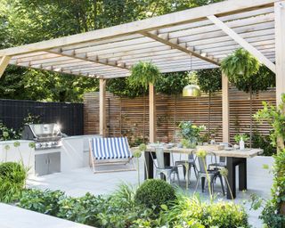Pergola mirrors the wooden slat fence, defining an outdoor dining area with BBQ