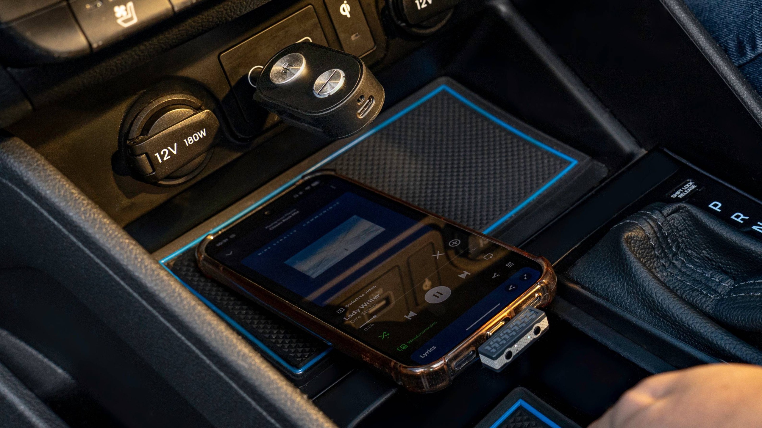 The iFi Up Travel Max connected to a car dash, with an iPhone underneath playing music.