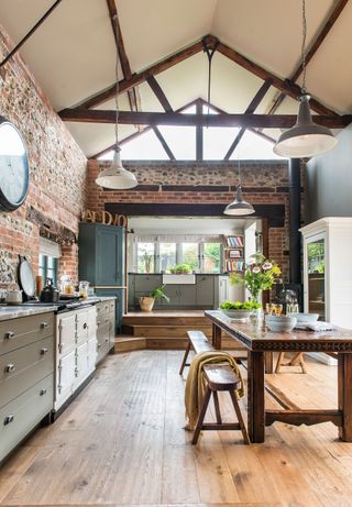 kitchen with beams brick walls and green units old dark wood carved table