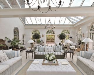 White and light blue orangery with fish motif cushions and nautical details, and huge chandeliers on the ceiling