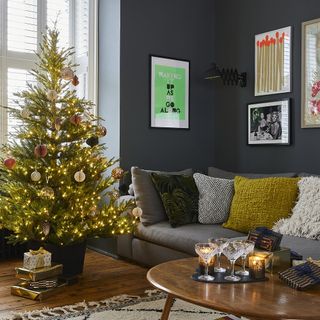 living room with dark grey walls and wooden flooring with wrapped gifts under Christmas tree