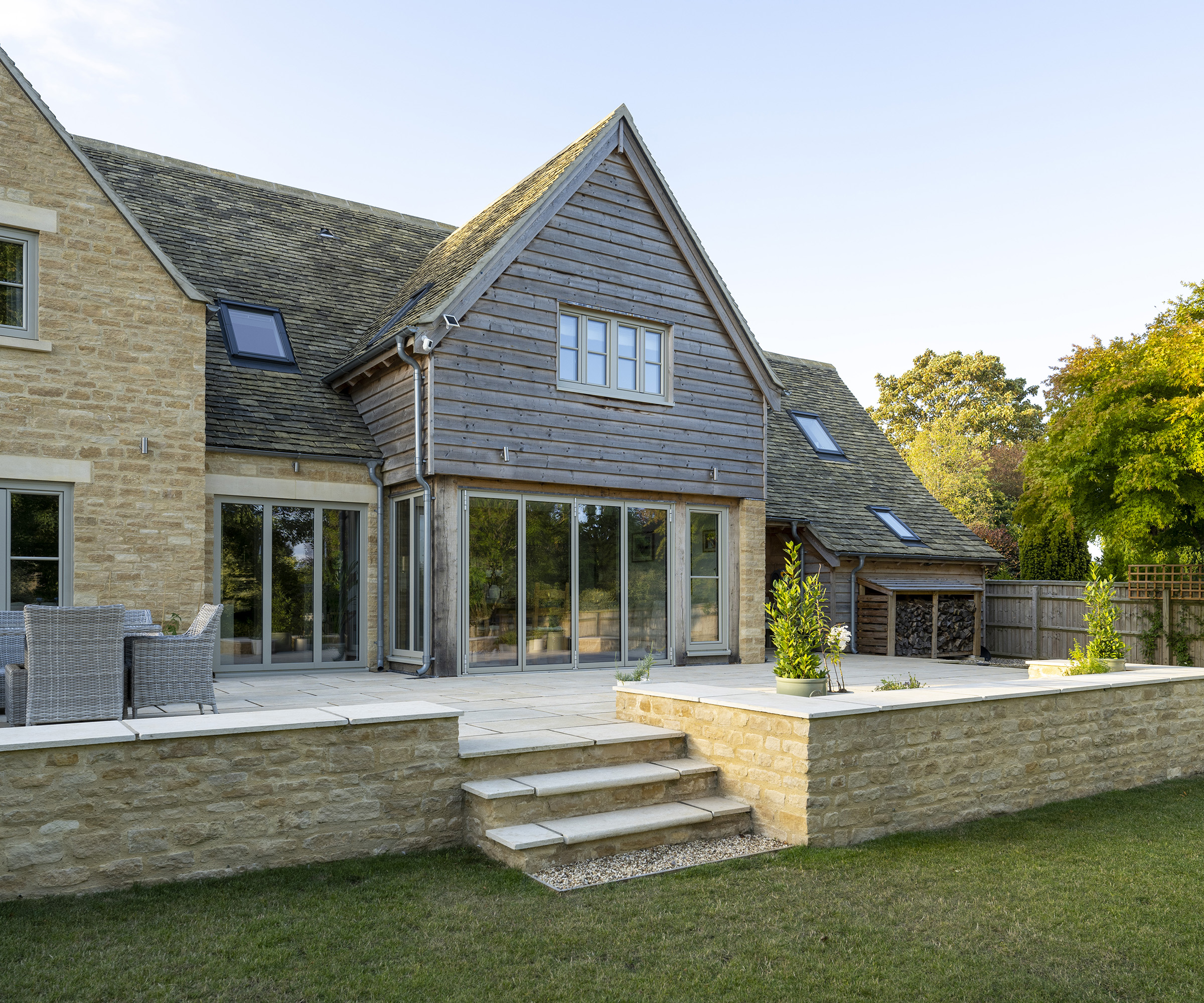 The rear exterior of an oak frame self build with timber and brick cladding and raised patio area