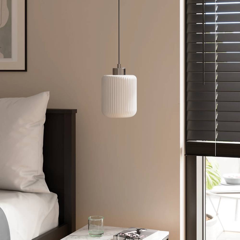 white fluted pendant light with silver cord next to bed