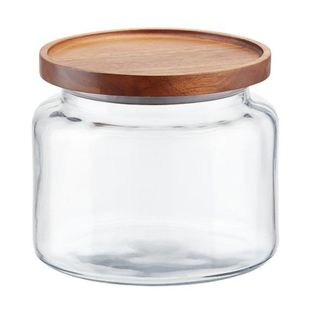 A wide glass round jar with natural wood lid