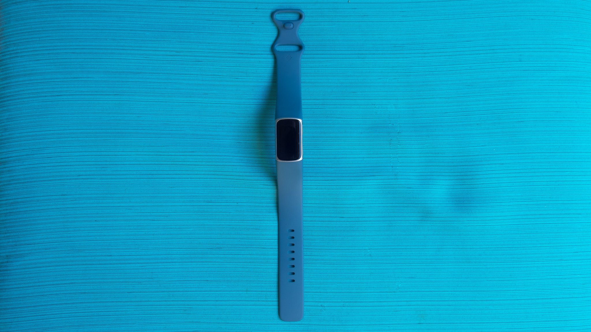 Fitbit Charge 5 sitting face-up on blue mat