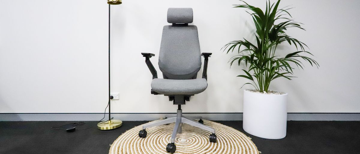 Steelcase Gesture in grey upholstery on a rug beside a floor lamp and potted plant