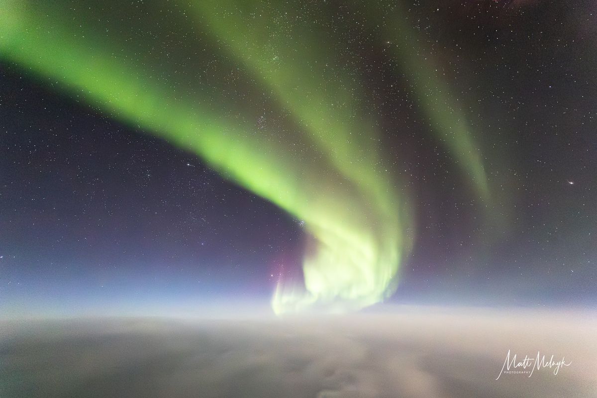 ribbons of green and purple light fill the sky in photos captured above the clouds from a dreamliner airplane.