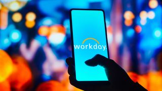 Workday logo appearing on a smartphone set against an out-of-focus cityscape at night with many lights producing bokeh