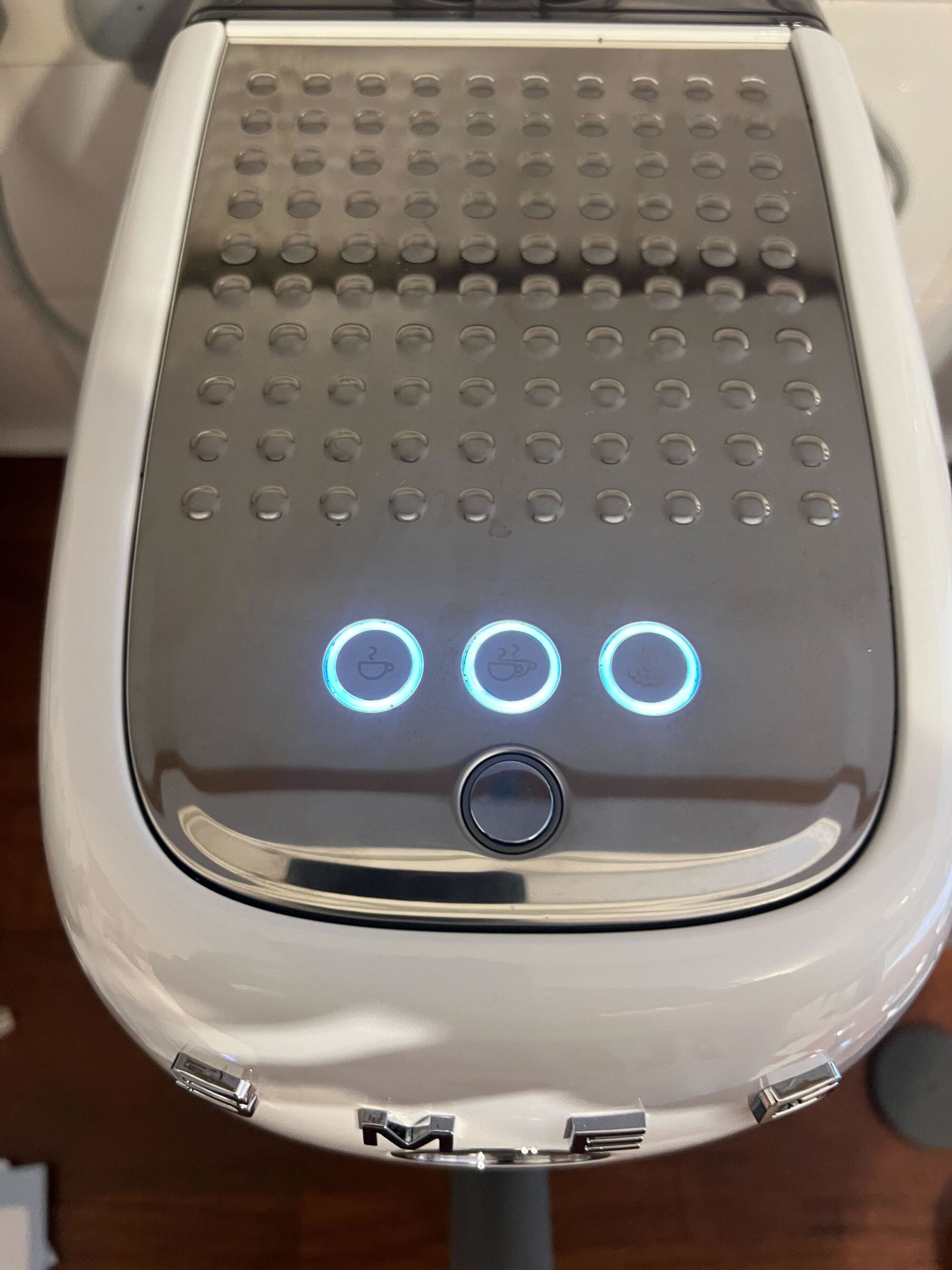 Close up image of the top of the Smeg cold brew machine with the three brewing buttons glowing with a white light.