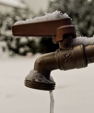 frozen outdoor faucet in winter with snow on ground