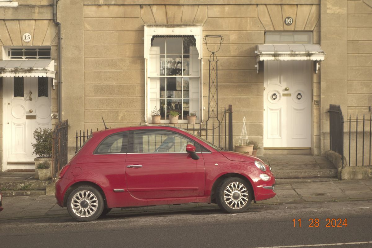 Red Fiat vehicle in the city of Bath, UK, with retro photo picture effect