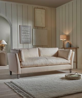 neutral panelled living room with all beige decor including a striped sofa and large textured rug