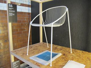 White steel shell chair, photographed on a wooden table