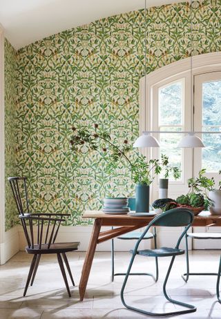 dining room with a wooden table a green traditional vine leaves wallpaper