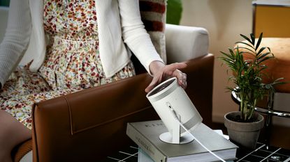 Samsung Freestyle projector placed on side table being adjusted by woman