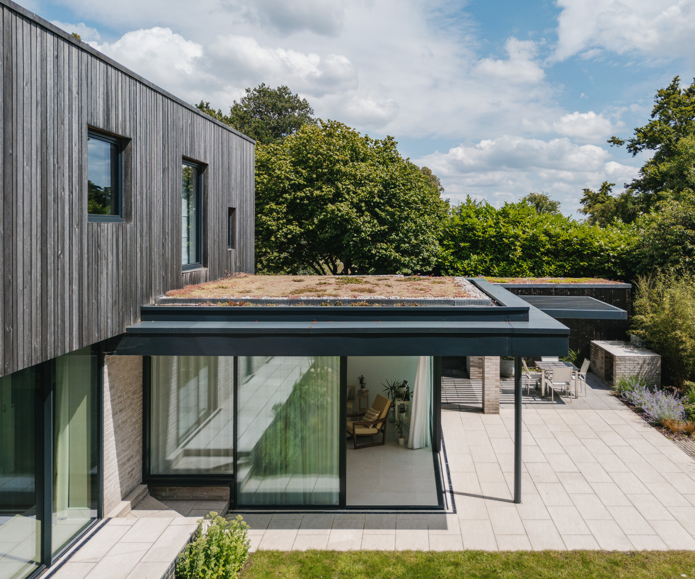 Exterior of a cladded house with a glazed extension on a white patio