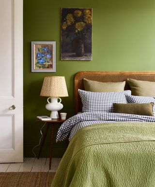 Green bedroom with wicker headboard, green throw, bedside table with lamp