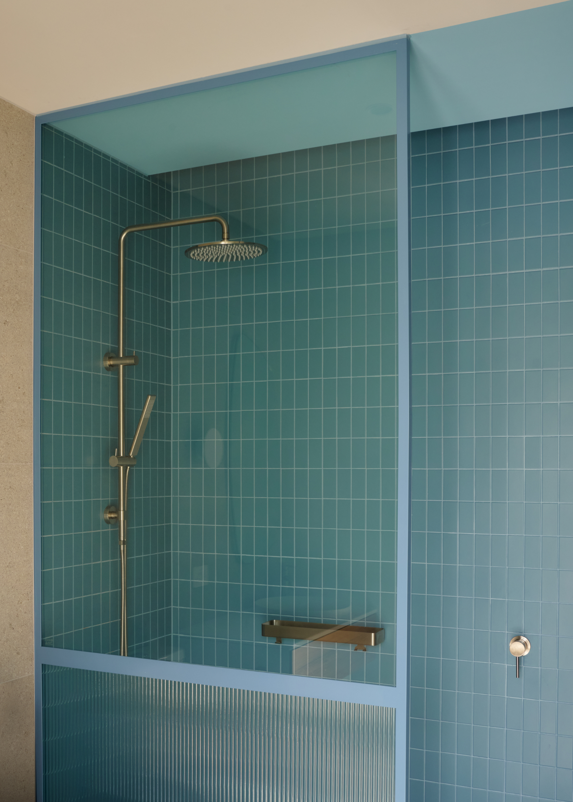 A bathroom with a blue tiled shower room and silver hardware