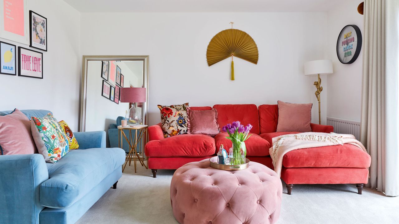 Living room with dark pink chaise-style sofa, blue sofa and round pink footstool