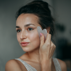 woman with glowing skin using a gua sha in her skincare routine