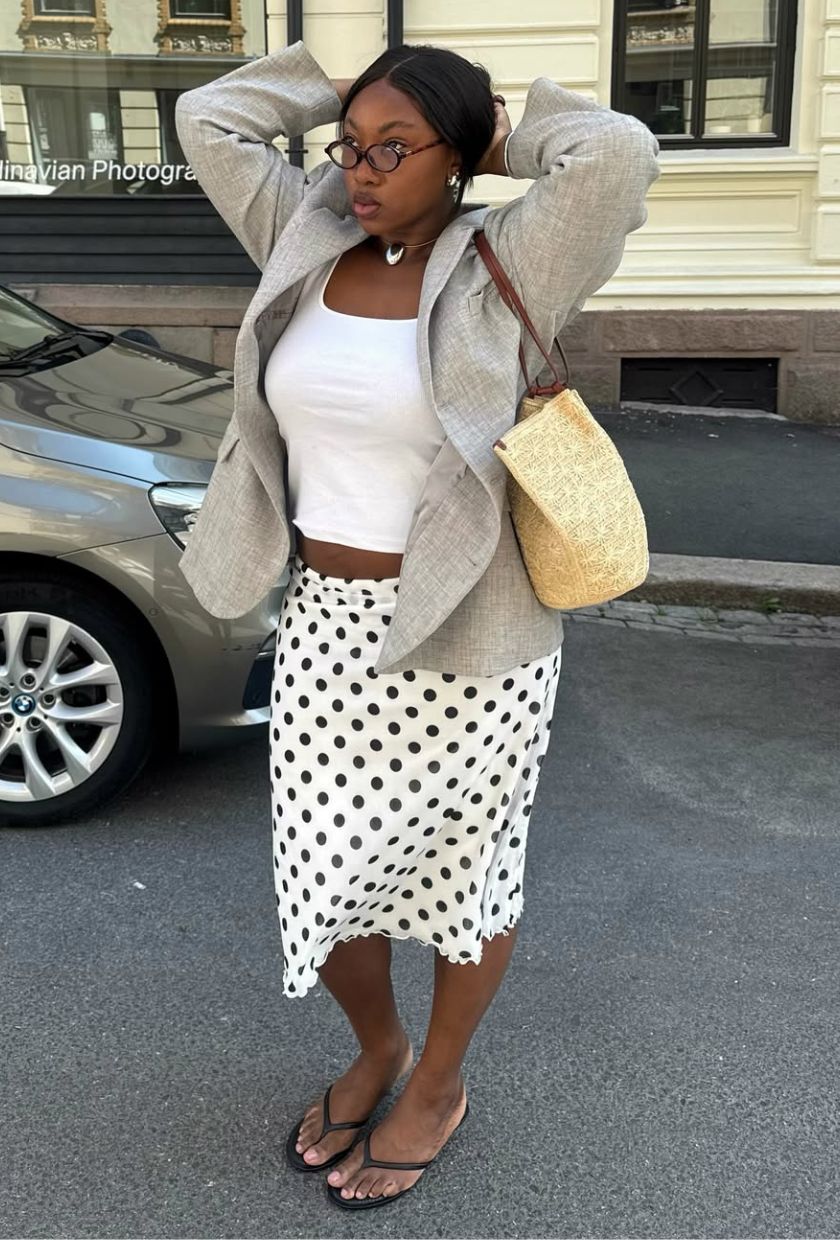 @nnennaechem wears a beige blazer, white tank top, polka-dot skirt, low-heeled sandals