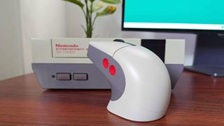 8Bitdo Retro R8 mouse on woodgrain desk with NES console in backdrop