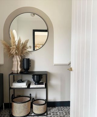 A small hallway with neutral decor, including black console table and cane baskets