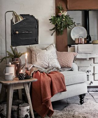 Kitchen Christmas decor ideas with an armchair in the corner of the kitchen near a range, with candles and blankets