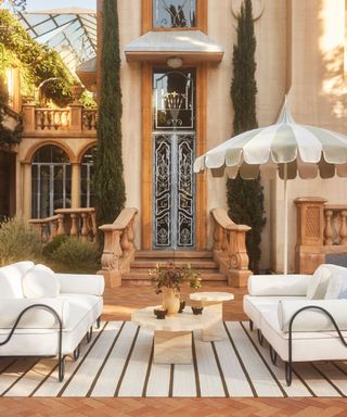 italian modern inspired villa patio styled with a striped rug, striped scalloped umbrella and iron furniture