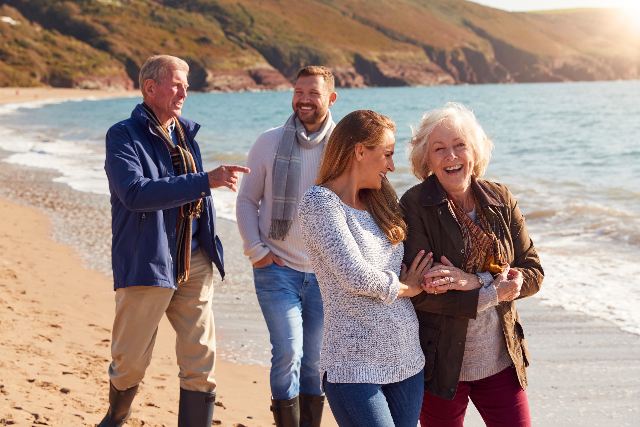 Senior Couple Walking Along Shoreline With Adult Offspring On a Winter Beach Vacation.