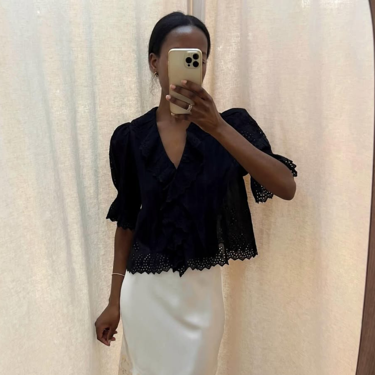 Sylvie in a black blouse and white lace-trim slip skirt
