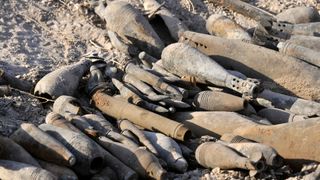 Piles of unexploded metal bombs lay on top of each other in the desert of Iraq