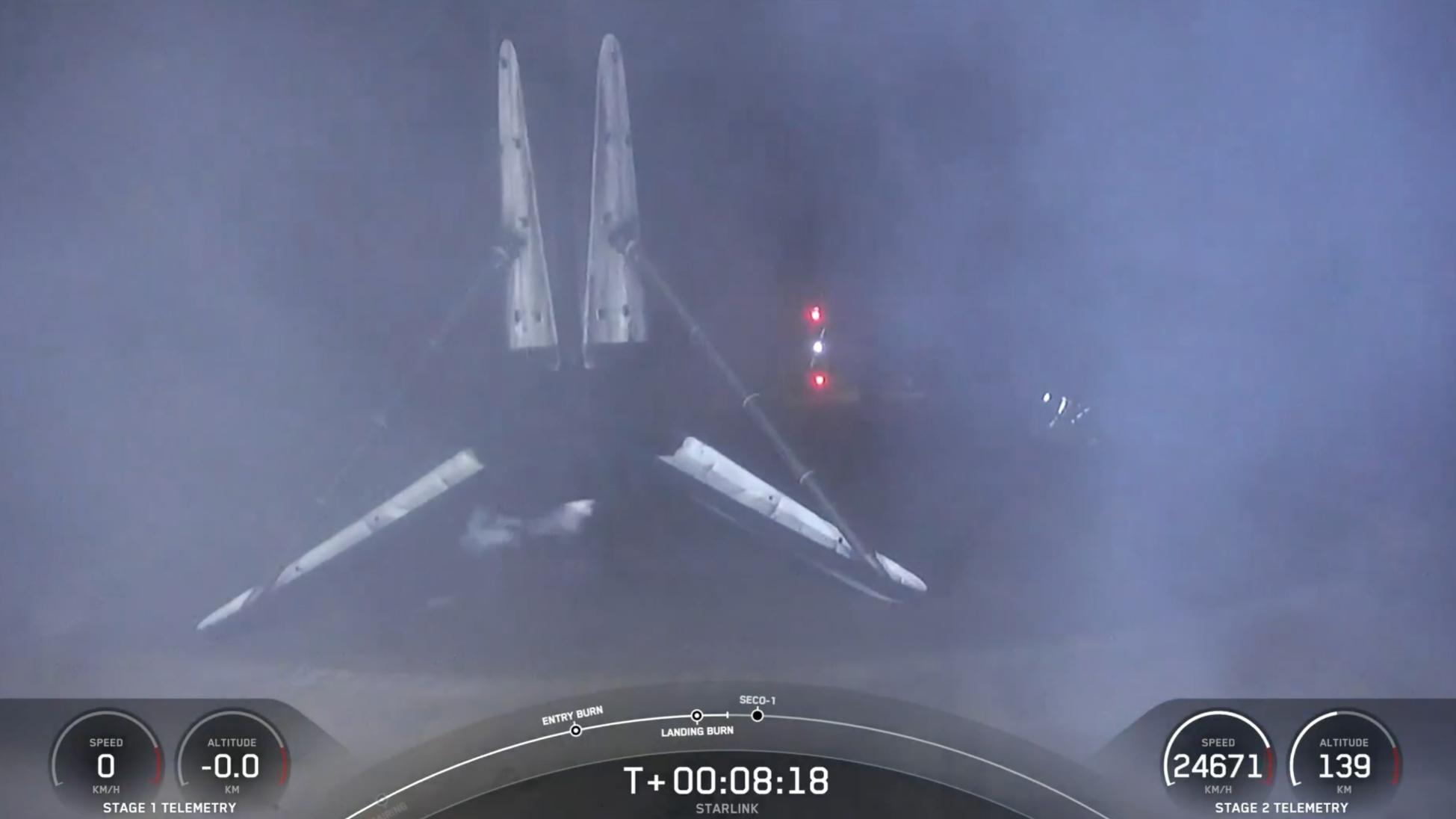 A black and white spacex falcon 9 rocket first stage sits on the deck of a ship at sea at night