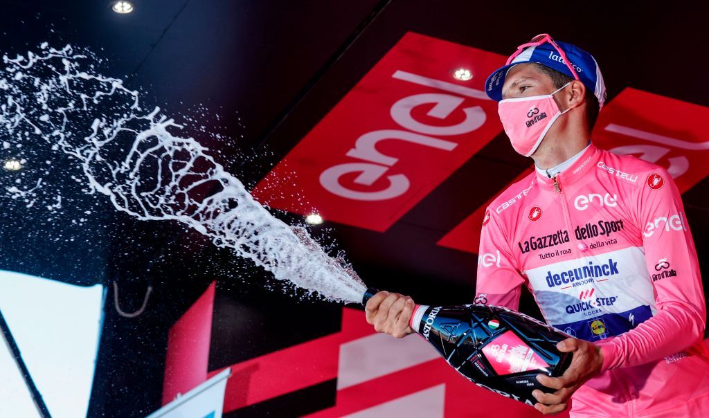 Team Deceuninck rider Portugals Joao Almeida wearing a face mask celebrates with a bottle of champagne on the podium after receiving the pink jersey in the 8th stage of the Giro dItalia 2020 cycling race a 200kilometer route between Giovinazzo and Vieste on October 10 2020 Photo by Luca Bettini AFP Photo by LUCA BETTINIAFP via Getty Images