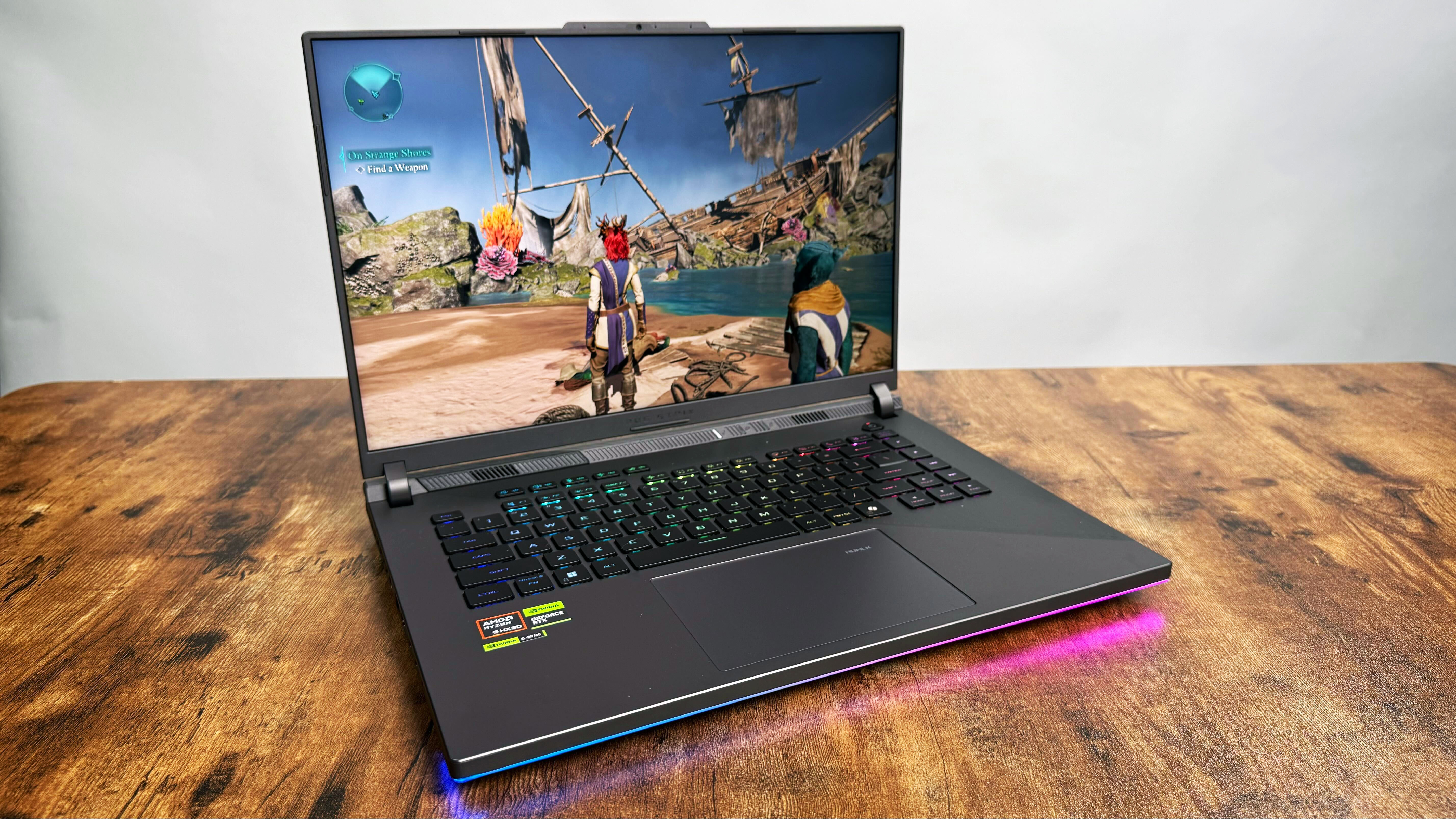 Asus ROG Strix G16 (G614FR) gaming laptop on a wooden desk against a gray background.