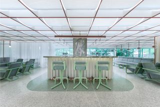 Spa reception area at Infinity Wellbeing, Bangkok with desk, chairs, terrazzo floors and view of outside greenery