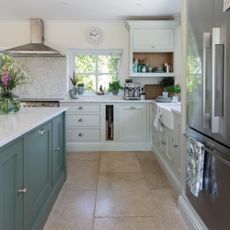two tone colour kitchen with sage green island, pale green units, stone flooring