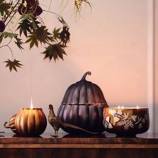 A Large Glass Gourd Gourmand Pumpkin & Sweet Vanilla Candle on a console table