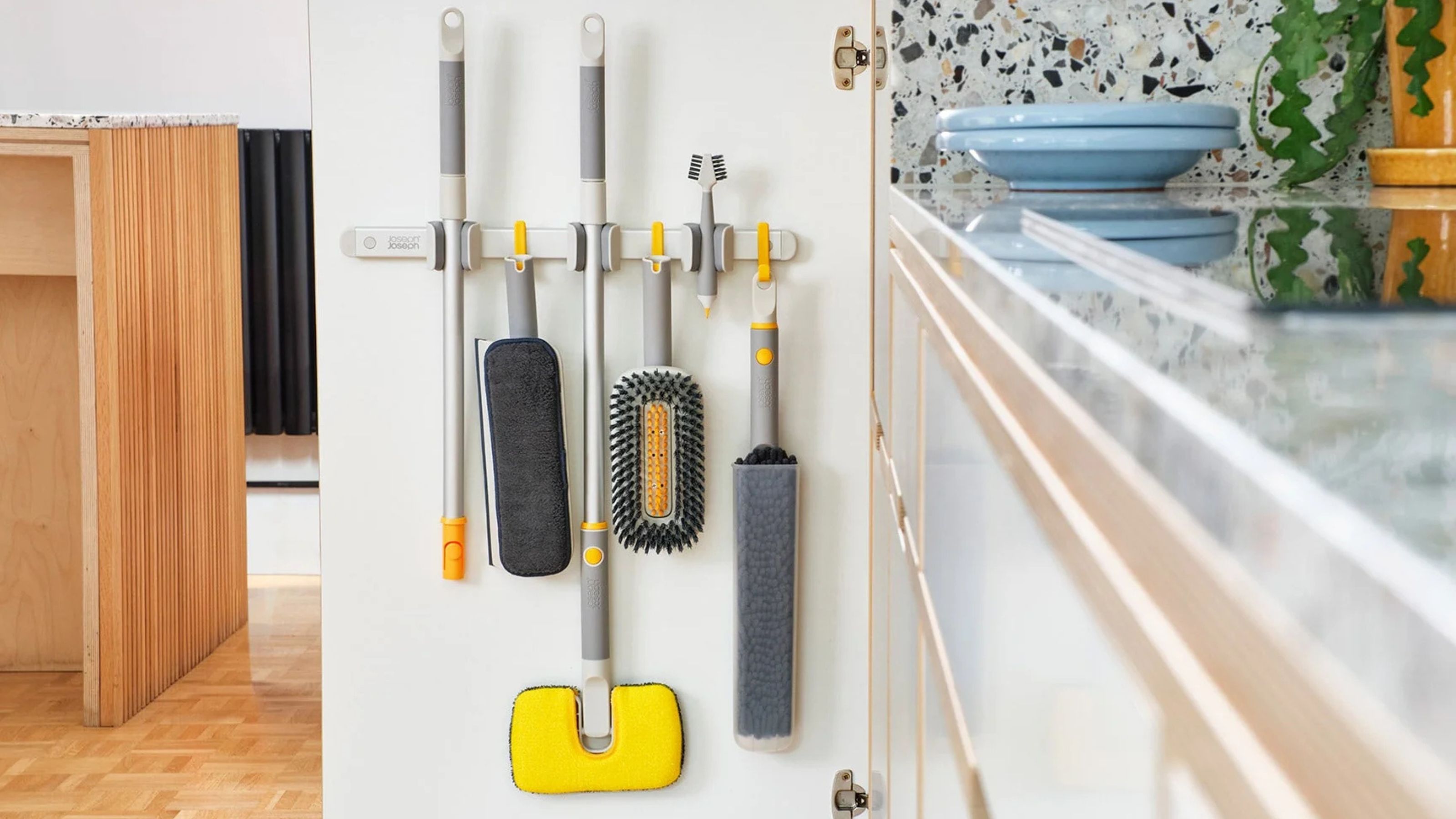 Joseph Joseph CleanTech cleaning tools hanging from the organiser on a white cupboard door