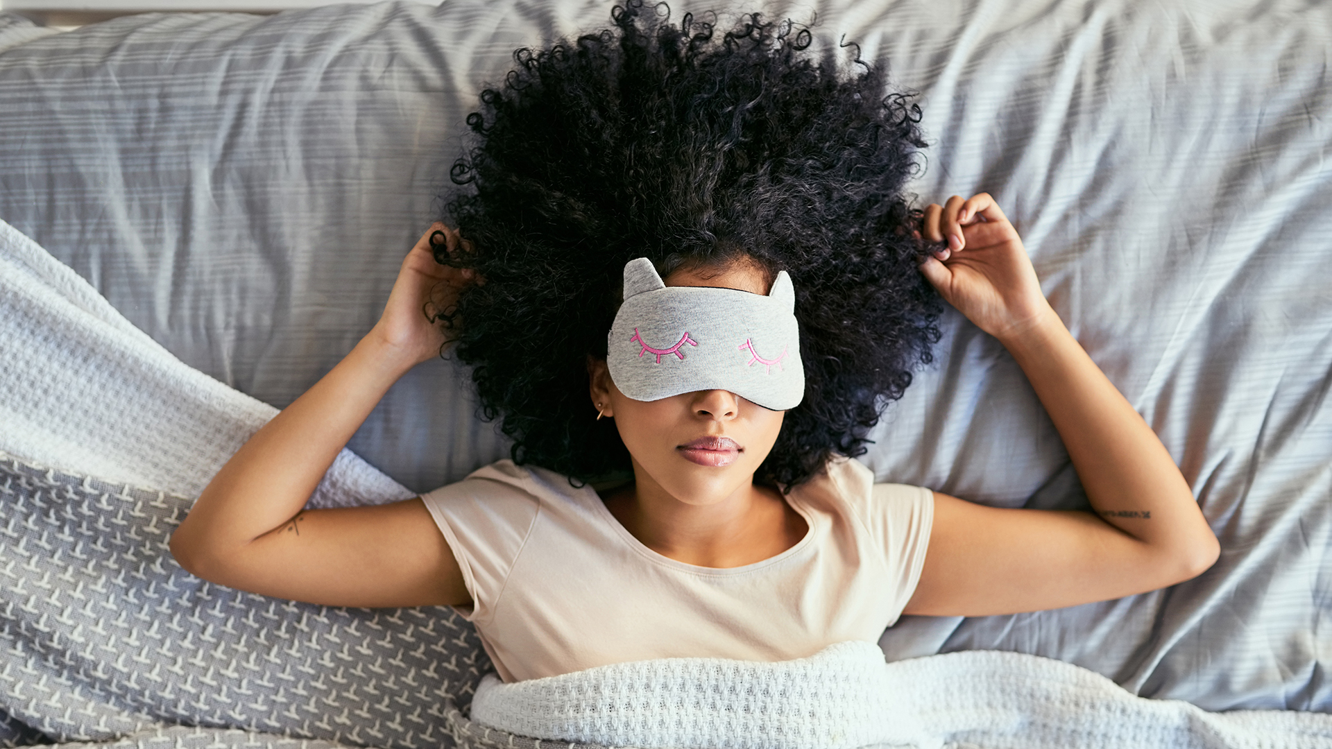 Una mujer que lleva una máscara para dormir yace en la cama
