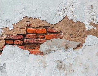 damaged render with exposed brick