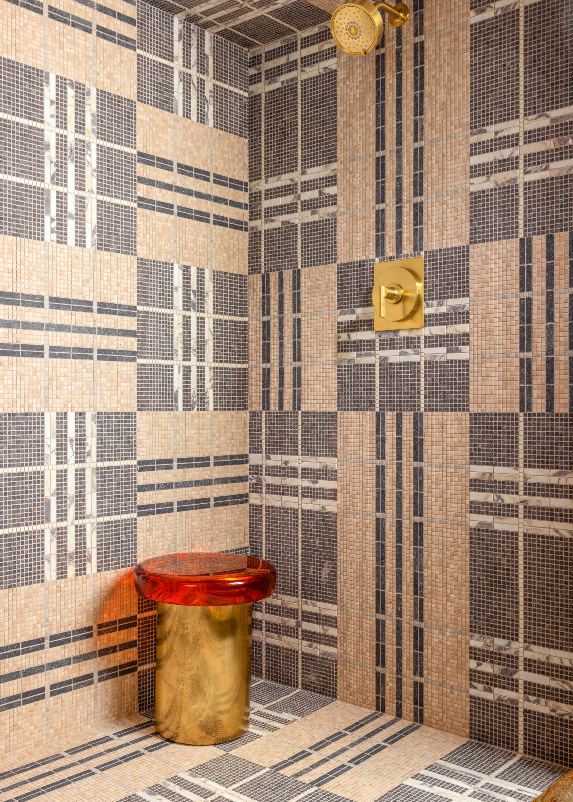 A pink and grey plaid tile design in an open shower room with gold hardware